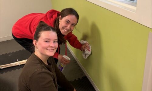 Two Safe Haven volunteers cleaning painting walls